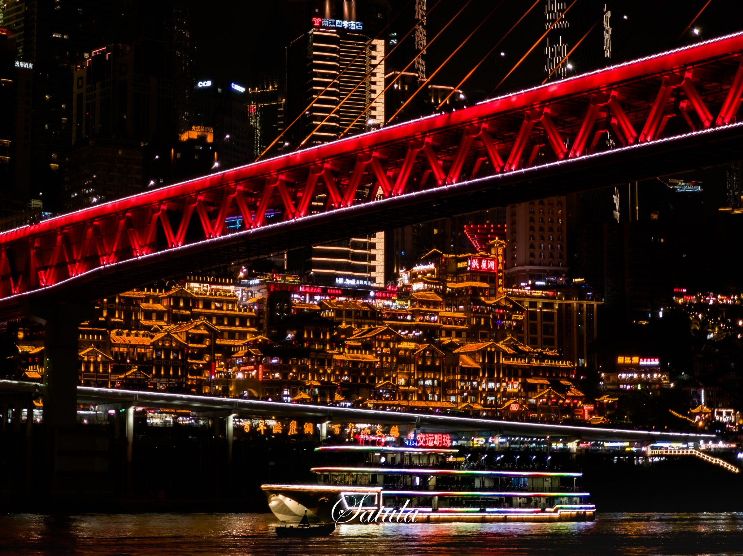 夜色里，红色桥梁横跨两岸，灯火映在江面。