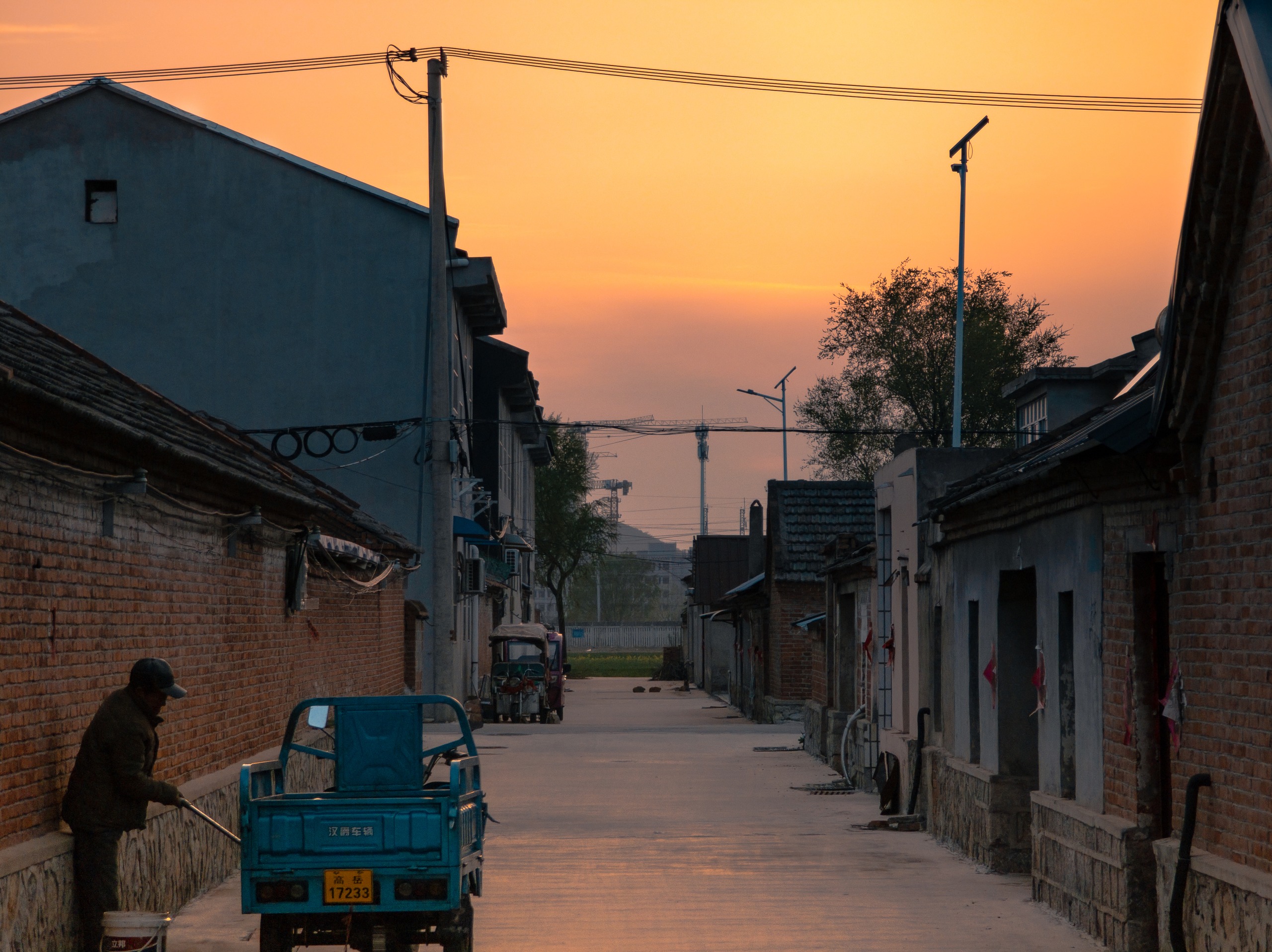 夕阳下的村巷与三轮车